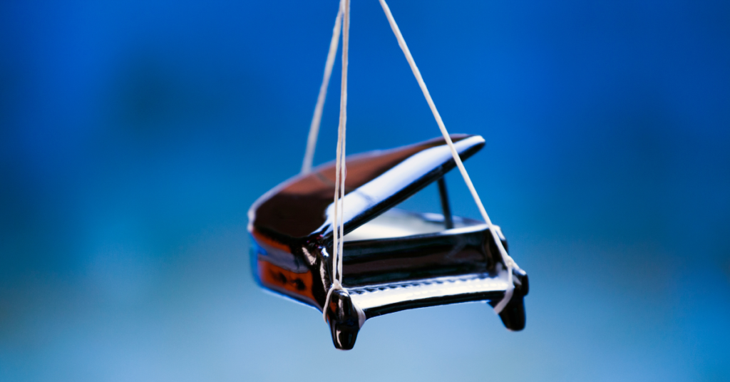 A tiny piano being held up by strings.