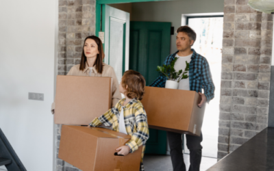 a family walking through the doorway of a house with moving boxes